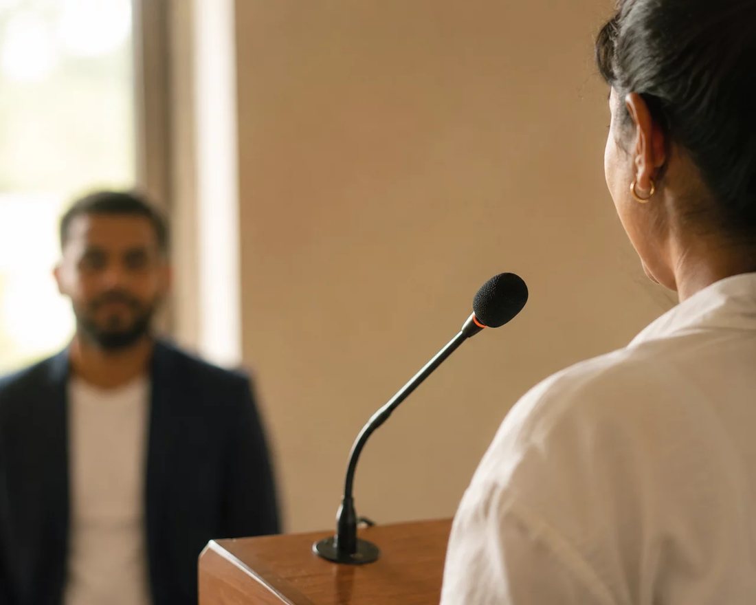 Participante ergue a mão para pedir a palavra numa mesa coberta de folhas anotadas